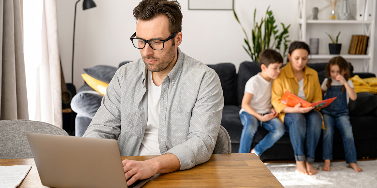 father doing budget items with family in the background