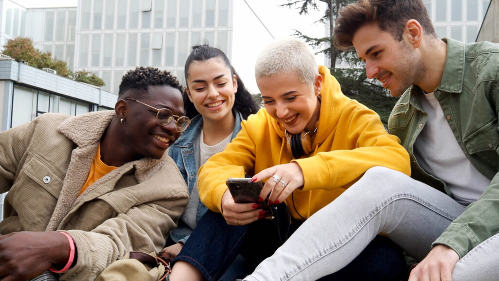 young people crowding around woman's phone and smiling