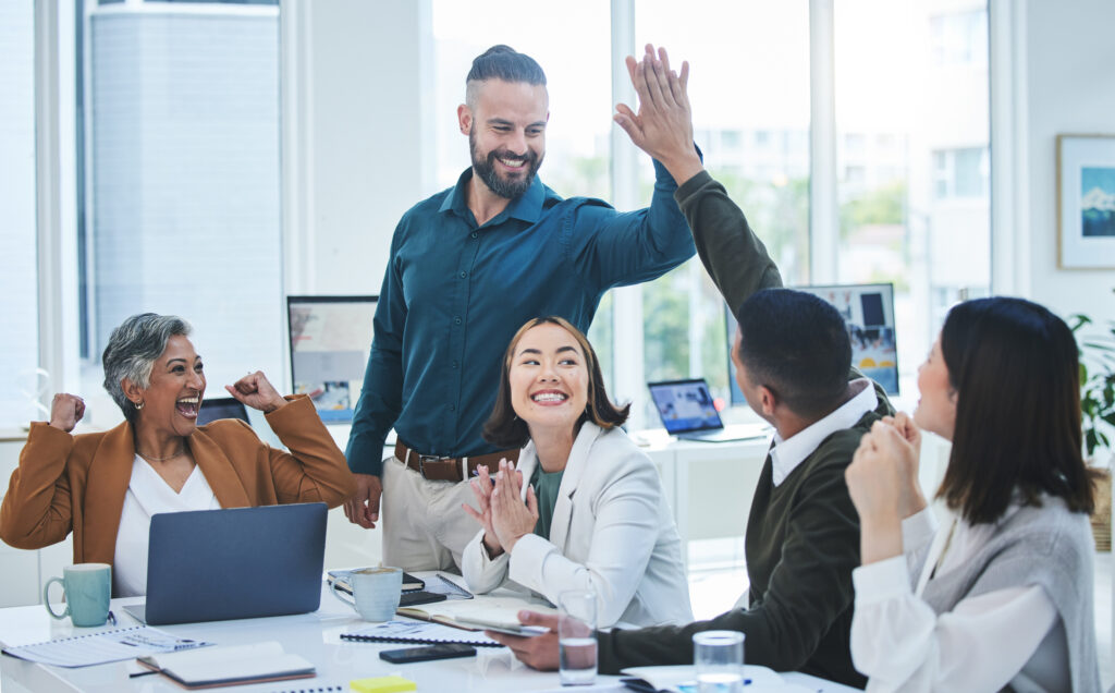 young professionals high fiving and smiling at a meeting
