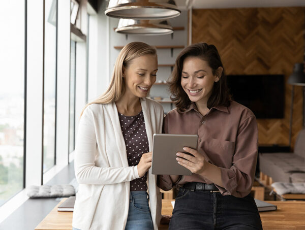 two professional women in modern office looking at tablet