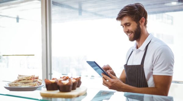 happy young cafe male employee on tablet