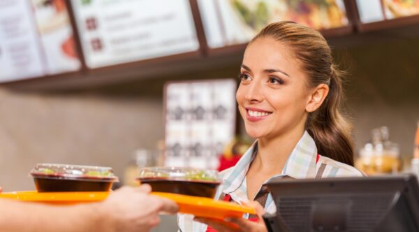 happy young restaurant worker handing food to customer